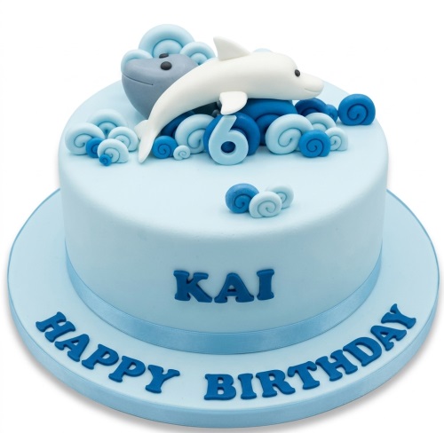 Light blue single-tier birthday cake with a white dolphin, grey whale, and blue wave decorations, featuring a custom age topper and personalised name.