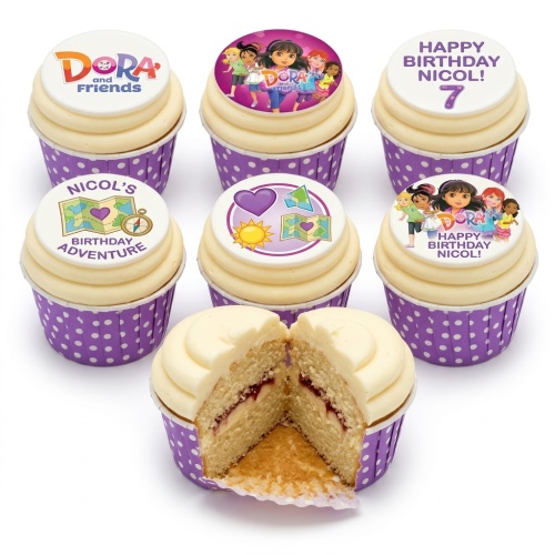 Dora and Friends themed birthday cupcakes with character and map toppers, purple polka dot wrappers, and one cupcake cut to show jam filling.