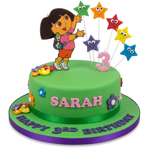 Green Dora the Explorer birthday cake with colourful stars, flowers, and custom age '3' and name 'Sarah'.