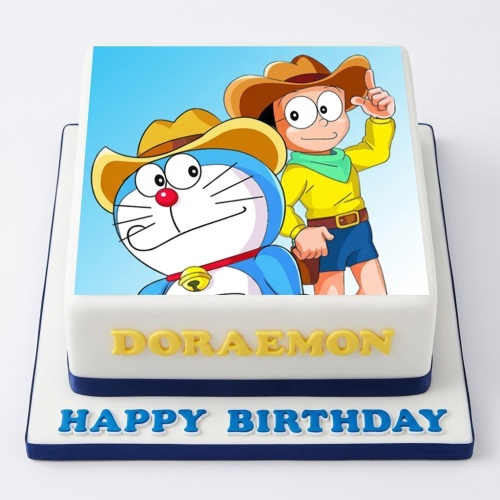 Square white cake with Doraemon and Nobita cowboy edible image, "DORAEMON" and "HAPPY BIRTHDAY" messages.