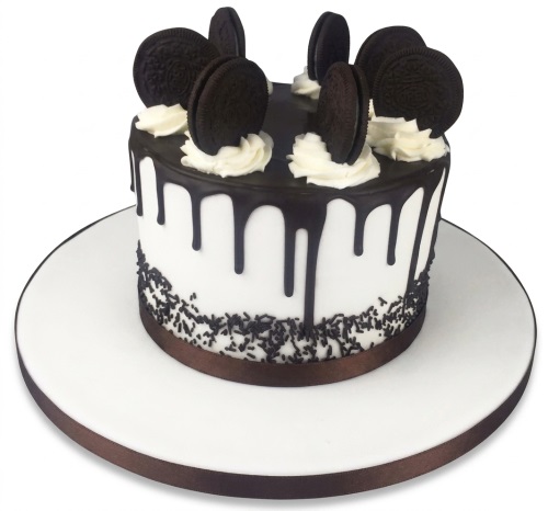 Round white cake with dark chocolate drip, Oreo cookies, and chocolate sprinkles.