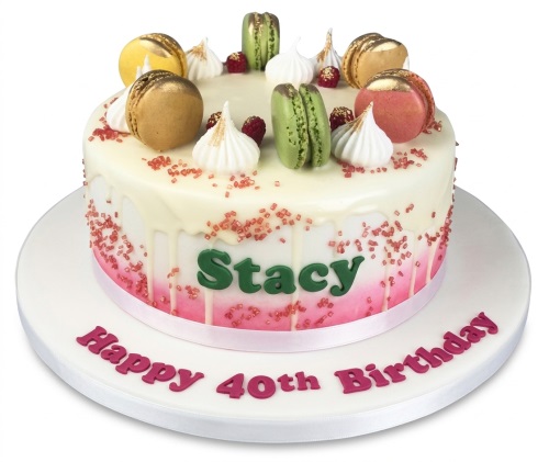 Round white and pink ombre drip cake with green, gold, and pink macarons, meringues, and raspberries.
