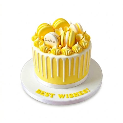 Yellow drip birthday cake with white and yellow macarons and meringue swirls.