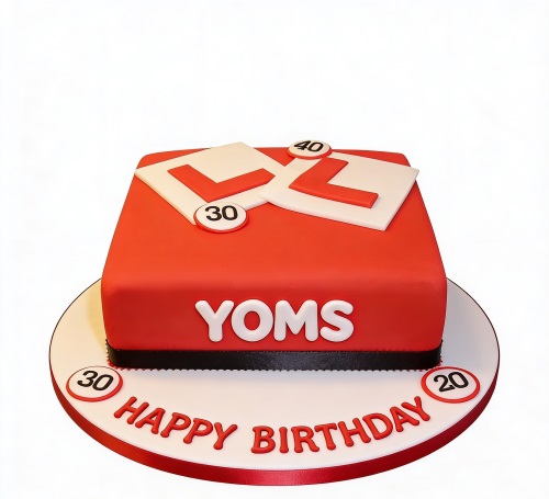 Red square birthday cake with white L-plates and various speed limit signs, with Happy Birthday text.