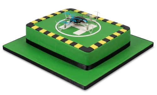 Green two-tier drone birthday cake with black and yellow hazard stripes and a drone model on a landing pad.