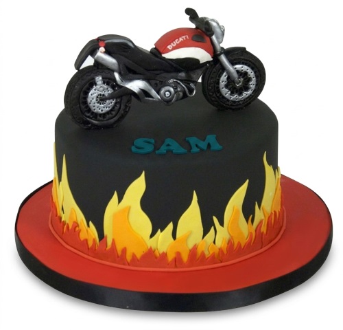 Motorcycle cake with black fondant and orange and yellow flames, topped with a red and black Ducati motorbike.