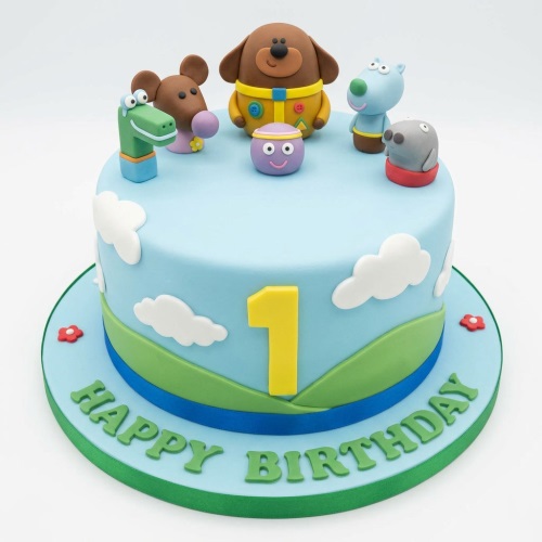 Hey Duggee 1st birthday cake with characters, clouds, hills, and a number one topper.