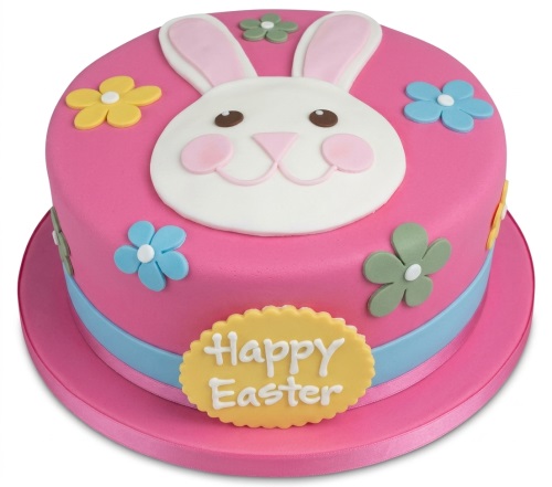 Pink round Easter cake with white bunny face, pastel flowers, and "Happy Easter" message.