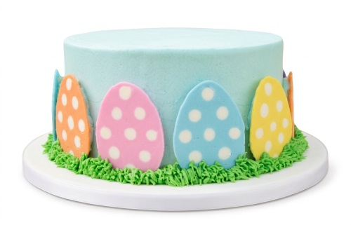 Round light blue cake with colourful polka dot Easter eggs and green grass piping.