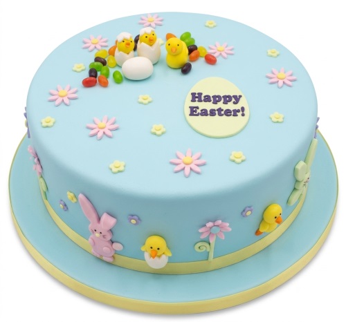 Round blue Easter cake with fondant chicks, bunnies, eggs, and pastel flowers.