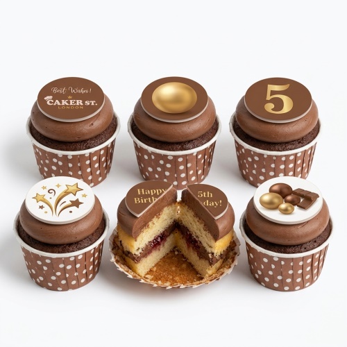 Chocolate cupcakes with brown and white polka dot liners, topped with chocolate frosting and various gold and chocolate themed decorations, including a custom age topper and a 'Happy Birthday' message.