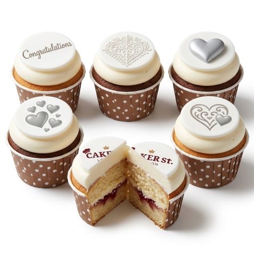 Six cupcakes with white frosting and fondant toppers. One says 'Congratulations', others have silver hearts and ornate heart patterns.