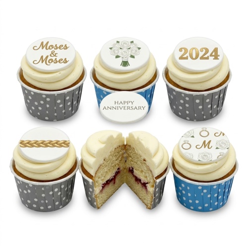 A selection of anniversary cupcakes with white frosting and customisable gold and white toppers, including roses, rings, a braid, and a year.