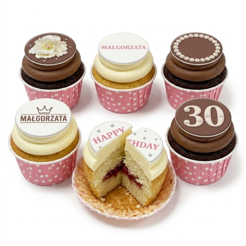 Selection of personalised birthday cupcakes in pink polka dot cases with custom name, age, and floral toppers.