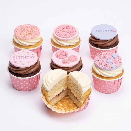 Assortment of pink and lilac floral lace design birthday cupcakes with 'HAPPY BIRTHDAY' messages.