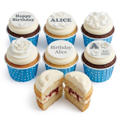 White frosted cupcakes with white floral decorations and personalised birthday toppers in blue cases.