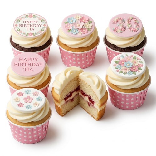 Floral birthday cupcakes with cream frosting and custom age or message toppers in pink polka dot wrappers.