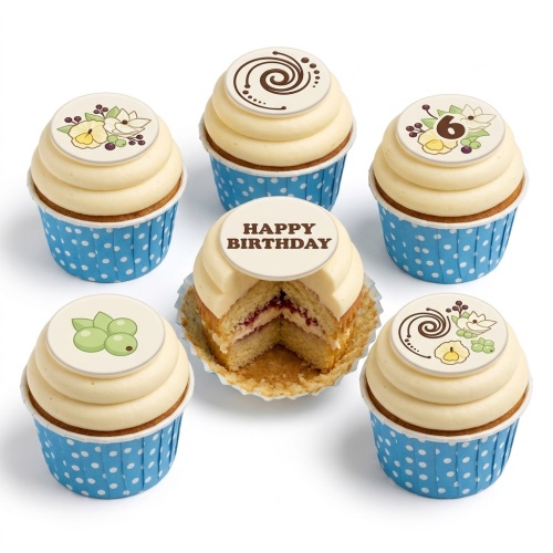 Six birthday cupcakes with cream frosting, blue polka dot wrappers, and decorative edible toppers including floral designs, a swirl, and 'Happy Birthday' message.