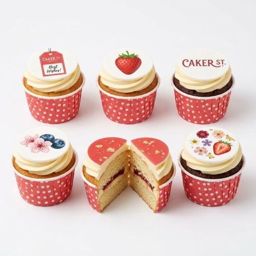 Cupcakes with white frosting, red polka dot wrappers, edible floral and fruit toppers, and 'Best Wishes!' message.