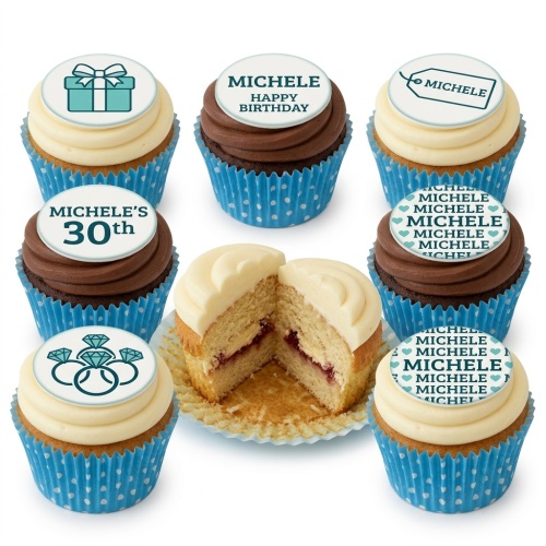 Assortment of vanilla and chocolate cupcakes with white and brown frosting, blue polka dot liners, and customisable birthday toppers including gift box, diamond rings, and personalised messages.
