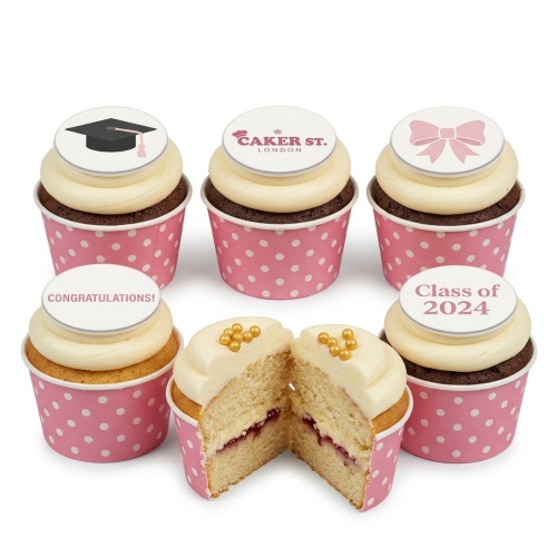 A set of six cupcakes in pink polka dot wrappers, featuring white frosting and various edible toppers including a graduation cap, a pink bow, "Congratulations!", "Class of 2024", and the Caker Street logo. One cupcake is cut in half, showing a vanilla sponge with jam filling and gold pearl sprinkles.
