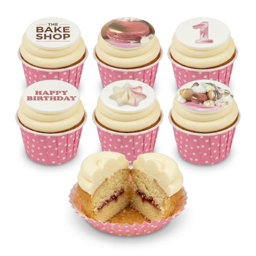 Vanilla cupcakes with cream frosting, pink polka dot cases, topped with macarons, meringues, and custom age/message discs.