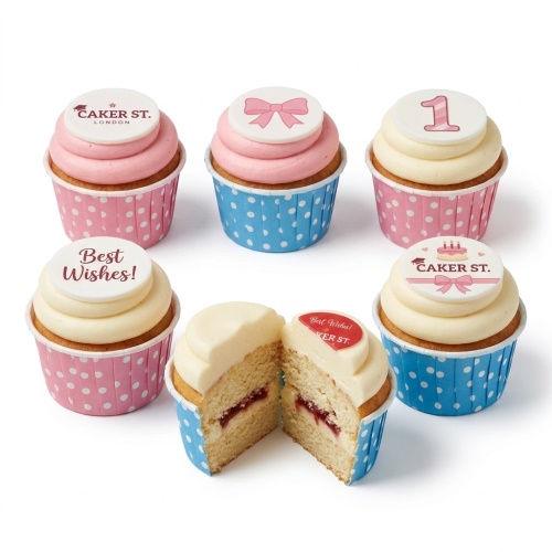 Cupcakes with pink and blue polka dot cases, topped with cream and pink frosting, featuring edible toppers with a pink bow, the number one, and "Best Wishes!"