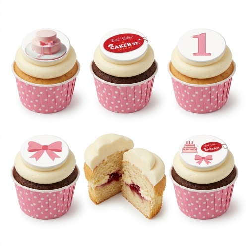 Six pink and white cupcakes with various toppers including a pink bow, a small pink cake, and the number one.