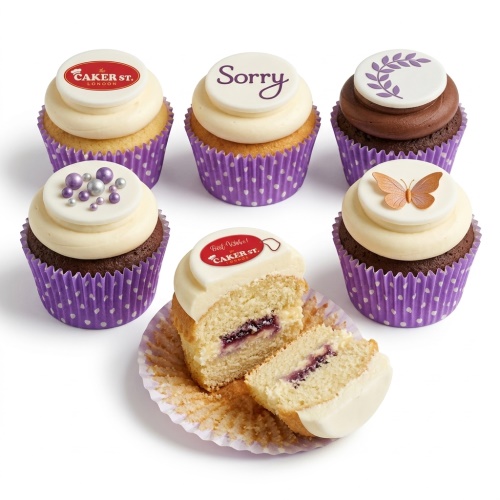 Assorted ladies birthday cupcakes with white frosting, purple cases, butterfly, floral, and sprinkle toppers.