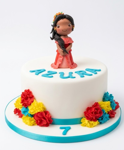 White round birthday cake with a flamenco dancer figurine, red, yellow, and blue flowers, and a custom age.