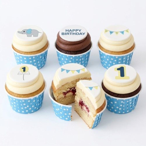 Six baby boy 1st birthday cupcakes with elephant, number one, and bunting toppers.