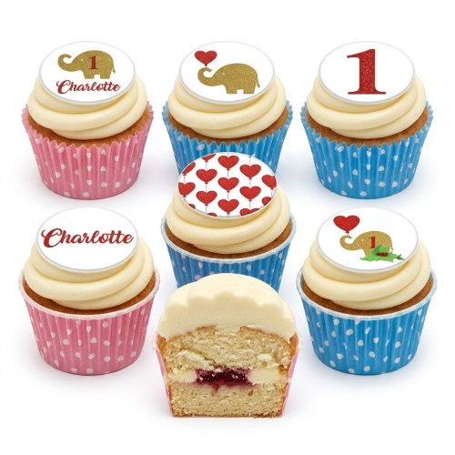 Vanilla cupcakes with white frosting, golden elephant, red heart, and number one toppers in pink and blue wrappers.