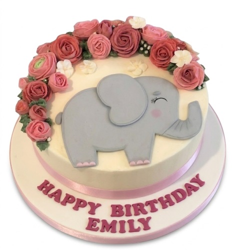 Round birthday cake with a grey elephant, pink and red buttercream flowers.