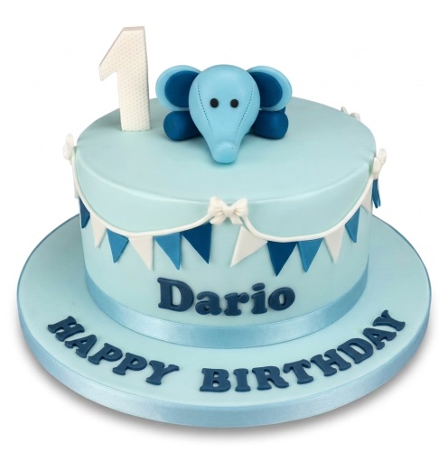 Light blue 1st birthday cake with a blue elephant topper, bunting, and a custom name.