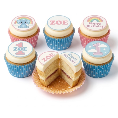 Six 1st birthday cupcakes with white frosting, pink and blue polka dot cases, and edible toppers featuring a baby elephant, rainbow, and number one.