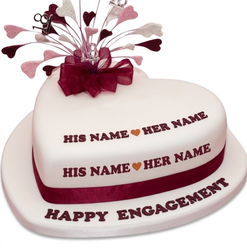 White heart-shaped engagement cake with burgundy ribbon, glitter heart topper, and custom message.