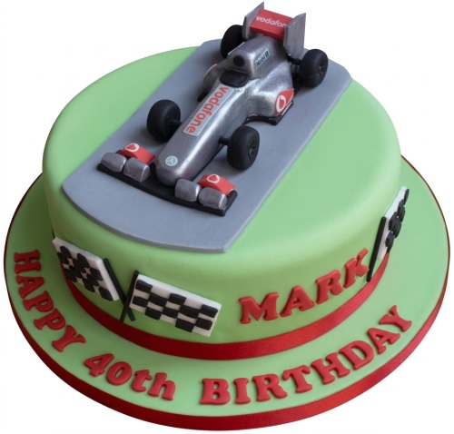 Round green two-tier birthday cake with a silver Formula One racing car topper and checkered flags.