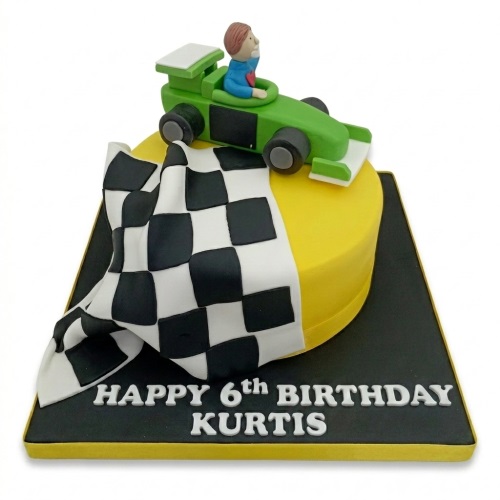 Yellow single-tier cake with green racing car, driver figurine, and black and white checkered flag for a personalised birthday.