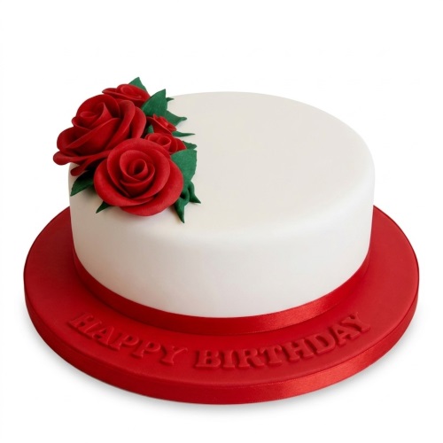 White round birthday cake with red fondant roses and green leaves on a red "Happy Birthday" board.