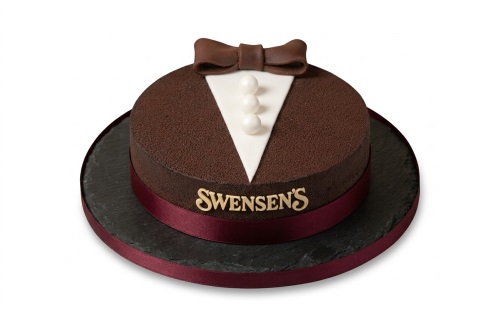 Round dark brown tuxedo cake with white shirt front, bow tie, and pearl buttons.