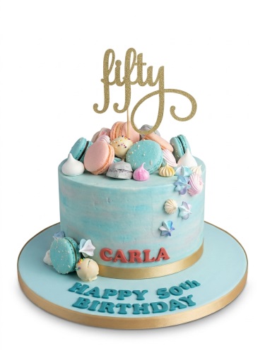 Pastel blue birthday cake with macarons, meringues, and a custom age topper.