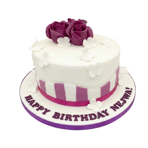 White round birthday cake with purple fondant roses, white flowers, purple and white stripes, and a pink ribbon.