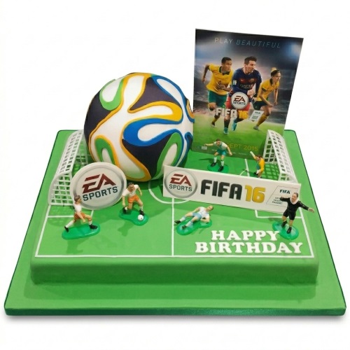 Green football pitch cake with 3D football, goals, player figurines, and FIFA branding.