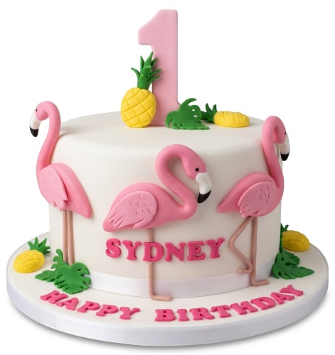 White round cake with pink flamingos, yellow pineapples, green leaves, and a pink number topper.