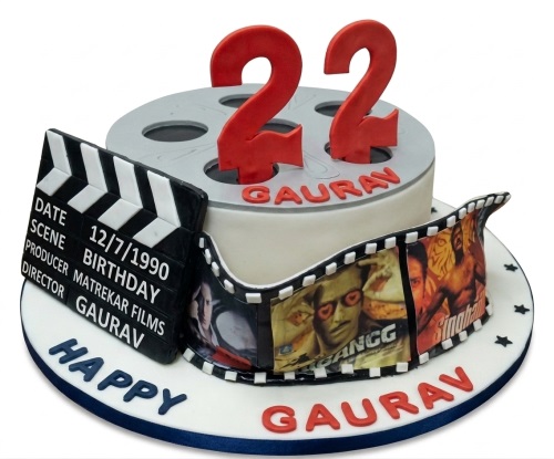 Two-tier movie theme birthday cake with film reel, clapperboard, film strip, and custom age topper.