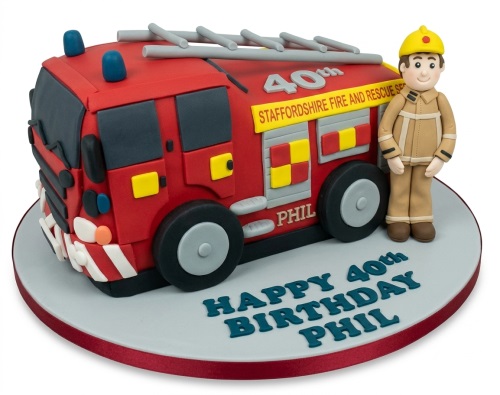 3D red fire engine cake with ladders and blue lights, a standing firefighter figure, and a grey cake board.