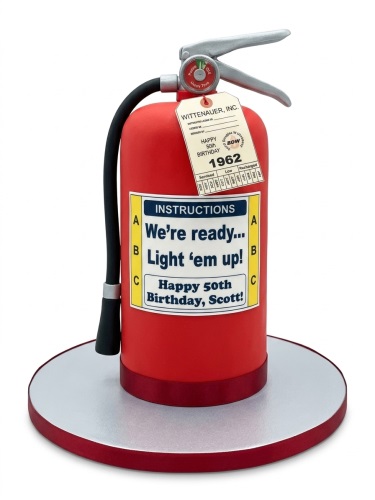 Red fire extinguisher shaped birthday cake with a 'Happy 50th Birthday' label.