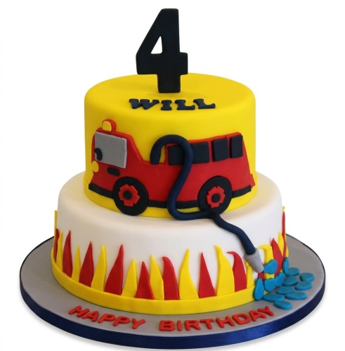 Two-tier fire engine themed birthday cake with a custom age topper and personalised name, featuring red and yellow flames and a fire hose spraying water.