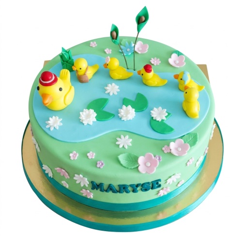 Round green cake with blue duck pond, yellow ducks, white water lilies, and pink flowers.
