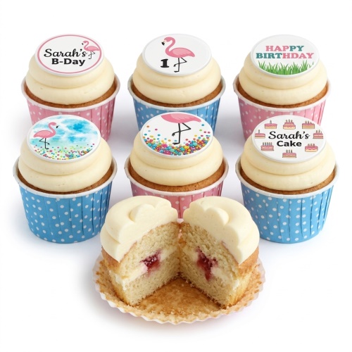 Six cupcakes with white frosting, pink flamingo toppers, and colourful sprinkles, one cut open to show jam filling.